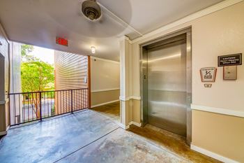 A hallway with a silver elevator and a sign on the wall.